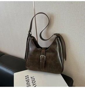 Gros plan d'un sac porté épaule marron rétro sur canapé en cuir avec boucles argentées