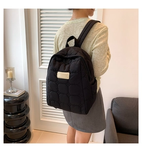 Close-up of black quilted nylon backpack featuring large grid stitching and beige patch