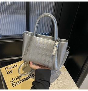 Detail of silver metallic handbag with diamond woven texture and dual top handles