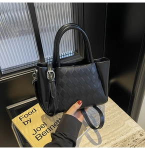 Close-up of black crossbody bag with quilted lattice texture and adjustable strap