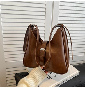 Vue détaillée d'un sac seau marron foncé avec boucle argentée et bandoulière chic
