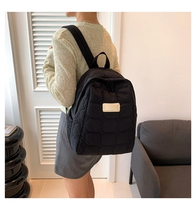 Detail eines schwarzen gesteppten Rucksacks mit hexagonalen Mustern und Trägern