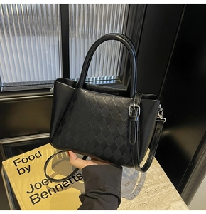 Close-up of black crossbody bag featuring a quilted lattice pattern and metal buckle