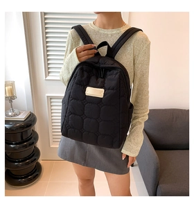 Detail eines schwarzen gesteppten Rucksacks mit wolkenartiger Textur und Lederetikett