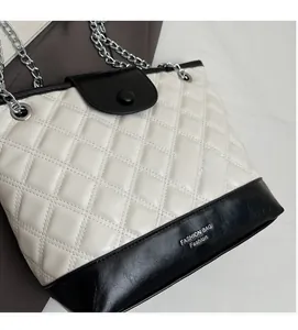 Detail of quilted leather texture and silver chain strap on a black and white bucket bag