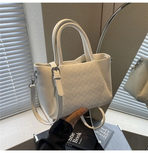 Detail of white quilted bucket bag with silver metal hooks and elegant top handles