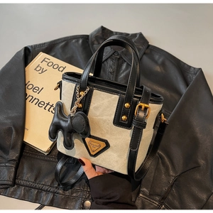 Détail du sac seau en toile avec garniture en cuir noir et breloque éléphant