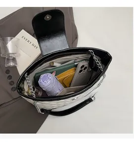 Spacious interior of white quilted bucket bag showing phone, umbrella and long wallet storage