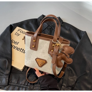 Détail du sac seau en toile avec finitions en cuir brun et pendentif ours en cuir