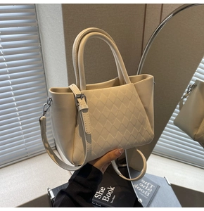 Detail of cream white tote bag featuring classic diamond quilted texture and silver hardware