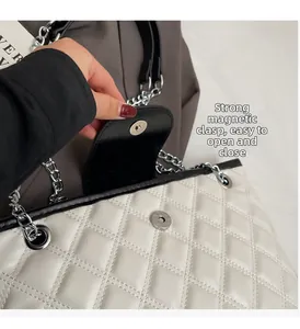 Close-up of the secure magnetic clasp on a white quilted leather bucket bag with chain