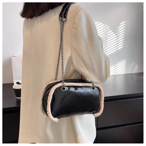 Model wearing a black leather chain bag with white wool trim in a modern indoor setting
