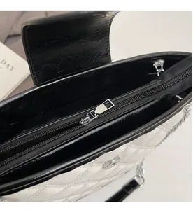 Close-up of white quilted handbag with black trim and silver smooth metal zipper