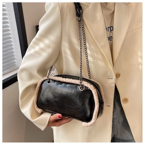Detail of black crossbody chain bag with plush fur trim on a model in chic beige blazer