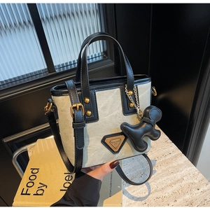 Détail du sac seau en toile avec finitions en cuir noir et breloque chien dorée