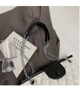 Close-up of white quilted bucket bag with black trim and silver hardware chain strap
