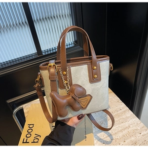 Détail du sac seau en toile avec bordure en cuir et breloque chiot décorative
