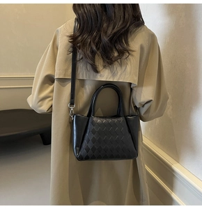 Detail of black quilted leather crossbody bag styled with a classic beige trench coat