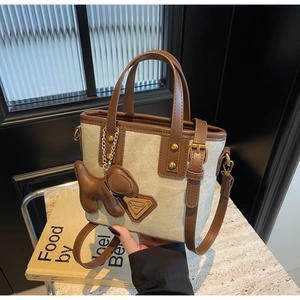 Détail du sac seau en toile avec garniture en cuir marron et breloque chiot mignonne