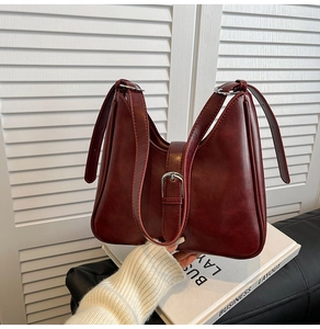 Gros plan du sac seau bordeaux avec boucle argentée et texture similicuir lisse