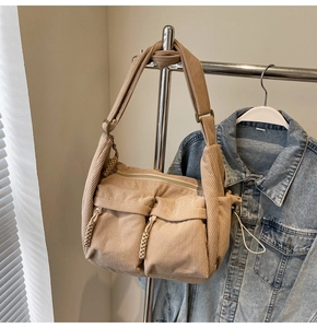 Detail der beigen Cord-Umhängetasche mit zwei Taschen und geflochtenen Reißverschlüssen