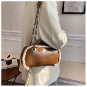 Detail of a brown leather shoulder bag with white faux fur trim and grey metal chain strap