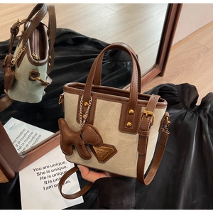 Vue détaillée du sac seau en toile avec garniture en cuir et breloque chiot sur velours