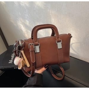 Vue détaillée du sac Boston marron avec ferrures argentées et charms de baseball