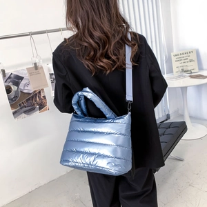Detail der metallisch blauen Stepptasche mit verstellbarem Riemen am Model