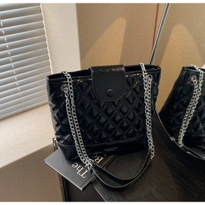 Detail of black quilted leather bucket bag featuring silver chain strap and fashion text