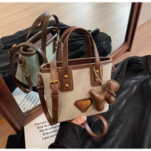 Détail du sac seau en toile avec garniture en cuir et breloque chien dans le miroir