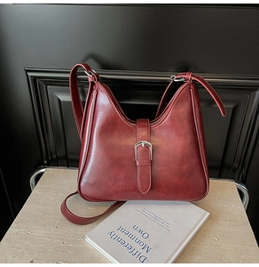 Détail du sac seau en cuir bordeaux vintage avec boucle en métal argenté sur pierre