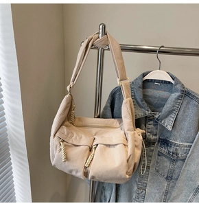 Detail der beigen Cord-Dumpingtasche mit zwei Reißverschlusstaschen am Kleiderbügel