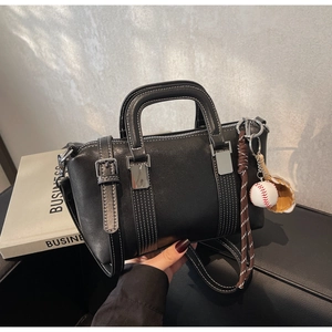 Vue détaillée du sac à main noir avec surpiqûres blanches et charme de baseball