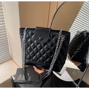 Detail of black quilted bucket bag featuring silver chain strap and polished PU leather