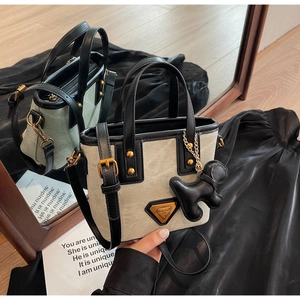 Vue détaillée du sac seau en toile rétro avec garniture en cuir et breloque chiot au miroir