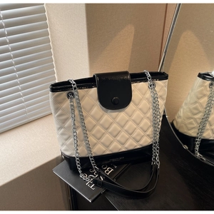 Detail shot of black and white quilted leather bucket bag with silver metal chain strap