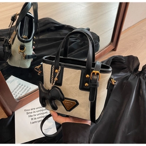 Détail du sac seau en toile avec bordure en cuir, chaîne dorée et charm chien mignon