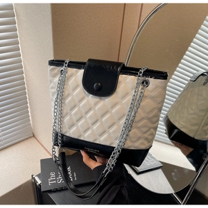 Close-up of quilted bucket bag with contrast black and white design and chain strap