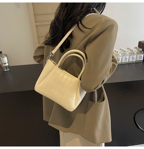 Chic cream woven bucket bag shown cross-body with refined leather texture and dual handles