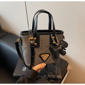 Détail du sac cabas en toile grise avec finitions cuir et plaque en métal triangulaire