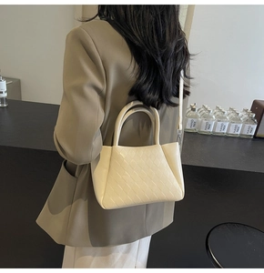 Detail showing beige crossbody bag with quilted texture and golden metal hooks