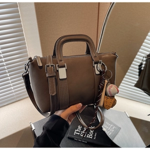 Détail du sac à main en cuir marron avec breloque de baseball et boucle en métal