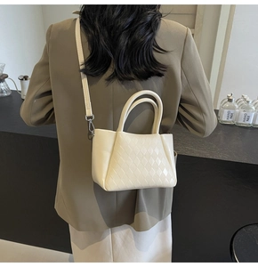 Rear view of cream-colored quilted crossbody bag worn with a brown blazer and skirt
