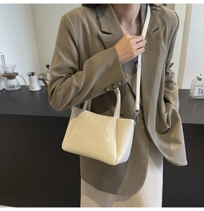 Detail of cream white quilted bucket bag with circular handles and silver hardware