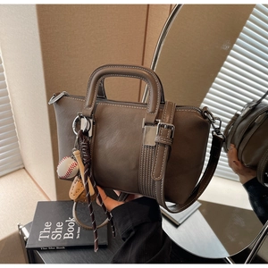 Détail d'un sac à main en cuir marron avec charme baseball et bandoulière réglable