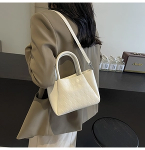 Detail of white quilted crossbody bucket bag showing woven texture and detachable strap