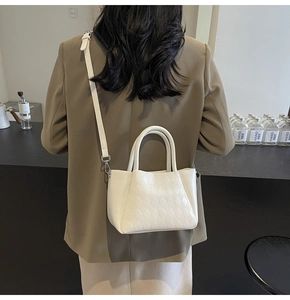 Detailed view of beige quilted bucket bag showing fine PU leather texture and hand straps
