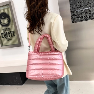 Detail einer rosa gesteppten Daunenhandtasche aus glänzendem Stoff mit Schultergurt