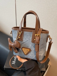 Sac seau en denim bleu avec garniture en cuir marron et breloque chiot à la main